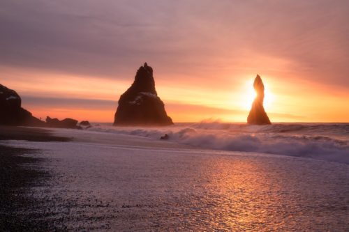 A figure on Reynisfjara gives scale to the large rock stacks at Vik Vik, Reynisfjara