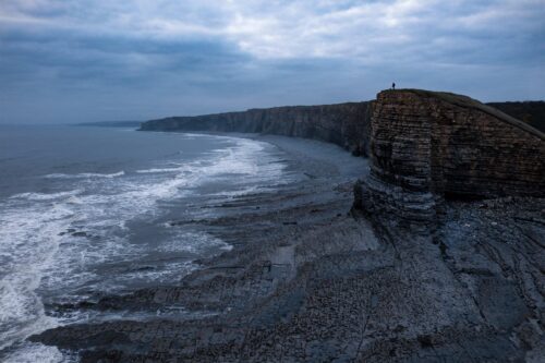 Dog walker gives scale to the majestic Nash Point of the Pembrokeshire Coast Nash Point, Pembrokeshire, Wales