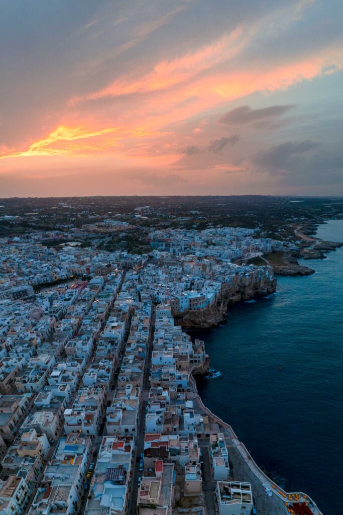 Sunset from Polignano a Mare with its white buildings, limestone cliffs and stunning clear waters Polignano a Mare, Italy, sunset, Puglia