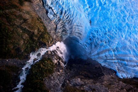 Birds eye view of a waterfall tumbling into Fox Glacier Fox Glacier, New Zealand