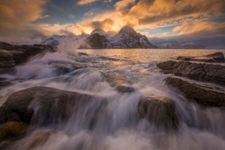 Sunset and splashes where the mountains meet the ocean, one of the characteristics of the Lofoten landscapes Lofoten, Vareid, Norway, winter