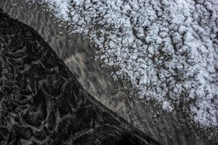 Abstract composition of snow on a black sand beach in Lofoten abstract, Skagsanden beach, Lofoten, Norway